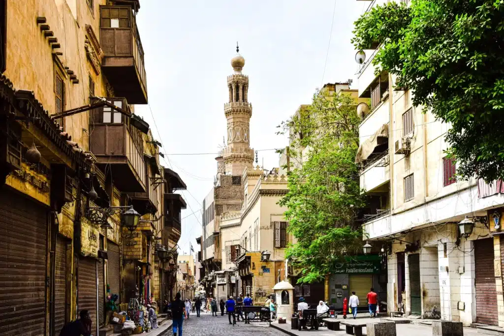 Sunlit historic street with a mosque minaret on Al Muizz Street