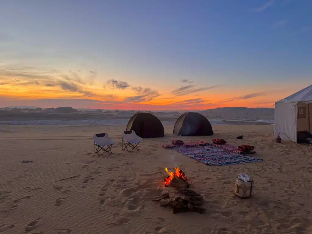 Campfire and tents at sunset in the White Desert