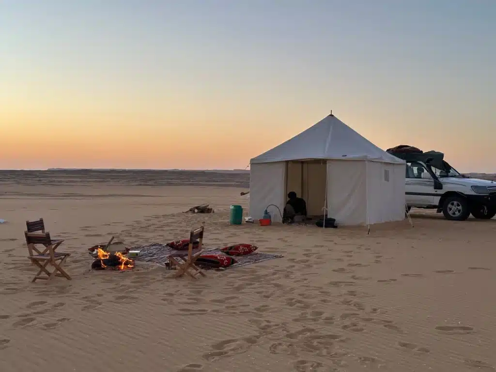 A canvas tent glowing at dusk in the White Desert