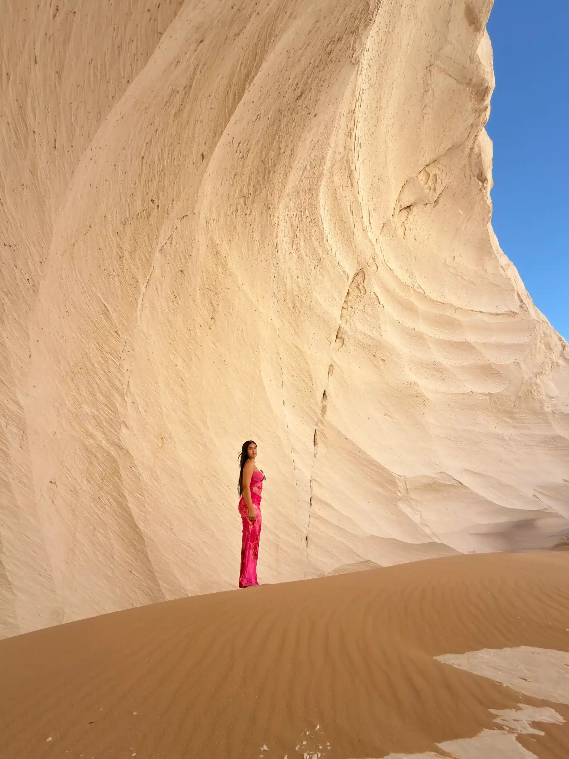 Woman in a pink dress beside a chalk wall in the White Desert, Egypt